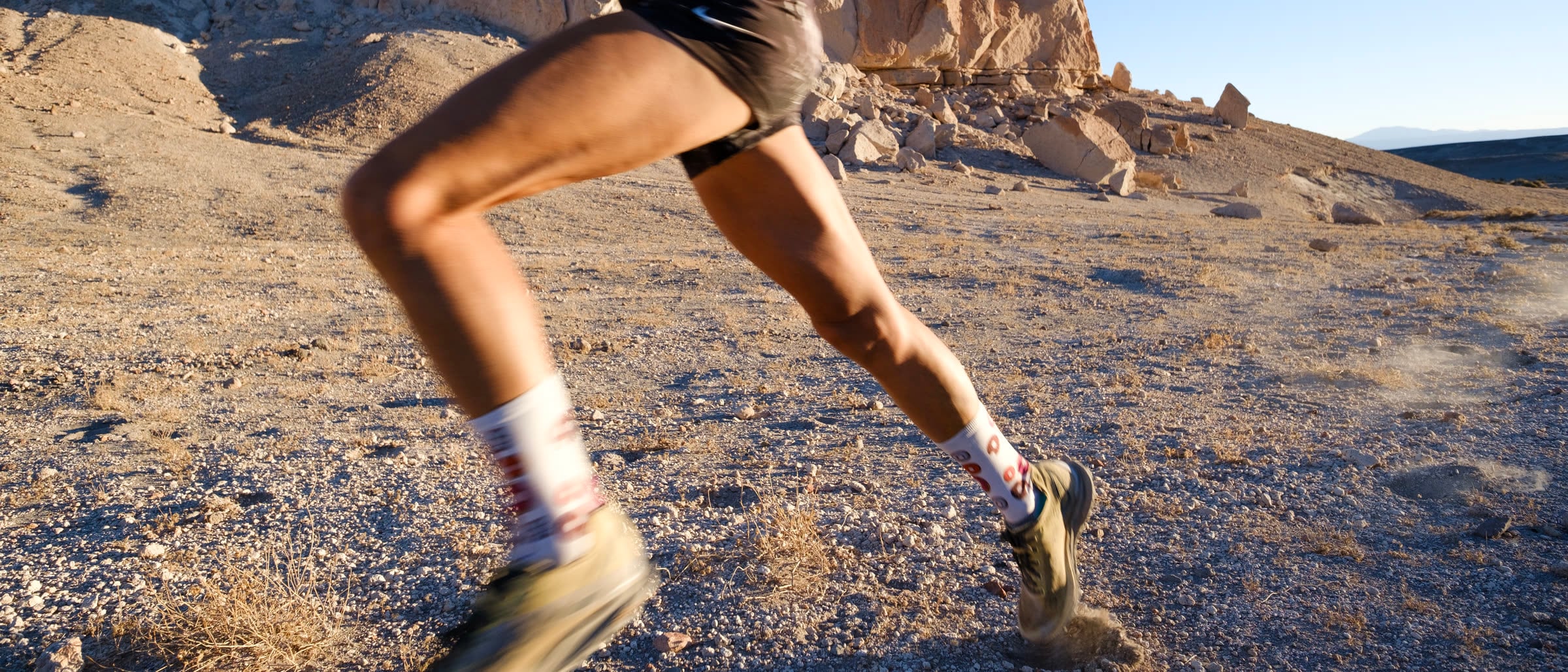 Atleta de DX3 corriendo en un terreno de arena y roca